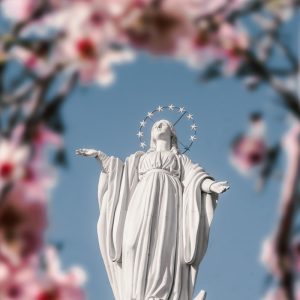 a statue of jesus surrounded by pink flowers