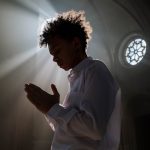 A Boy in White Polo Shirt Praying Inside a Church