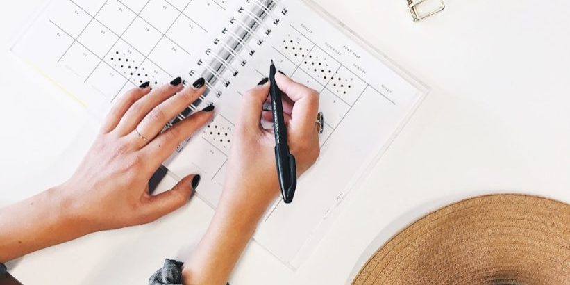 person holding ballpoint pen writing on white paper